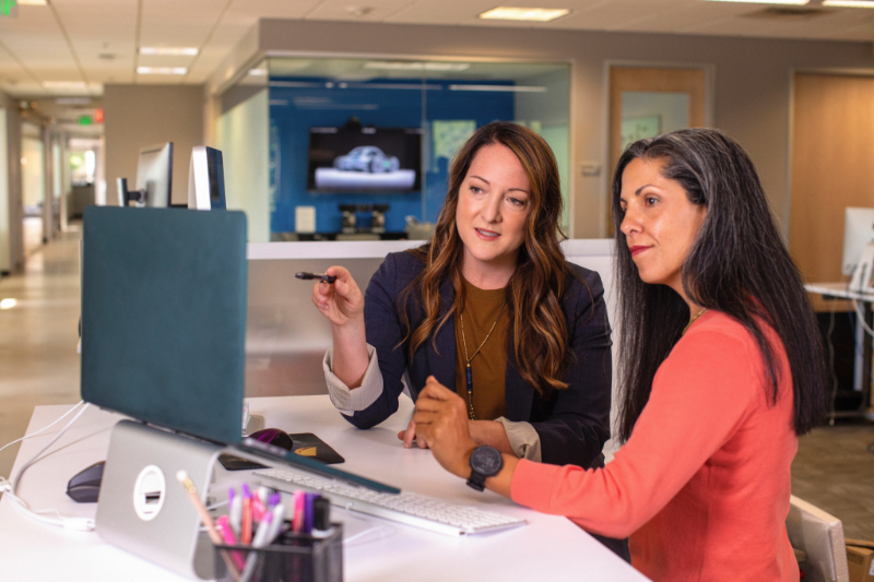 Two women working together in front of a laptop