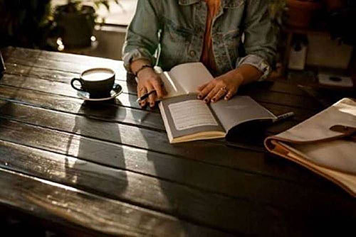 Person opening notebook on brown wooden table