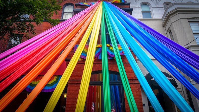 streamers displayed in rainbow order connecting to a brick building