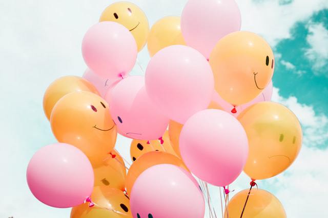 pink and yellow balloons with smiley faces on them