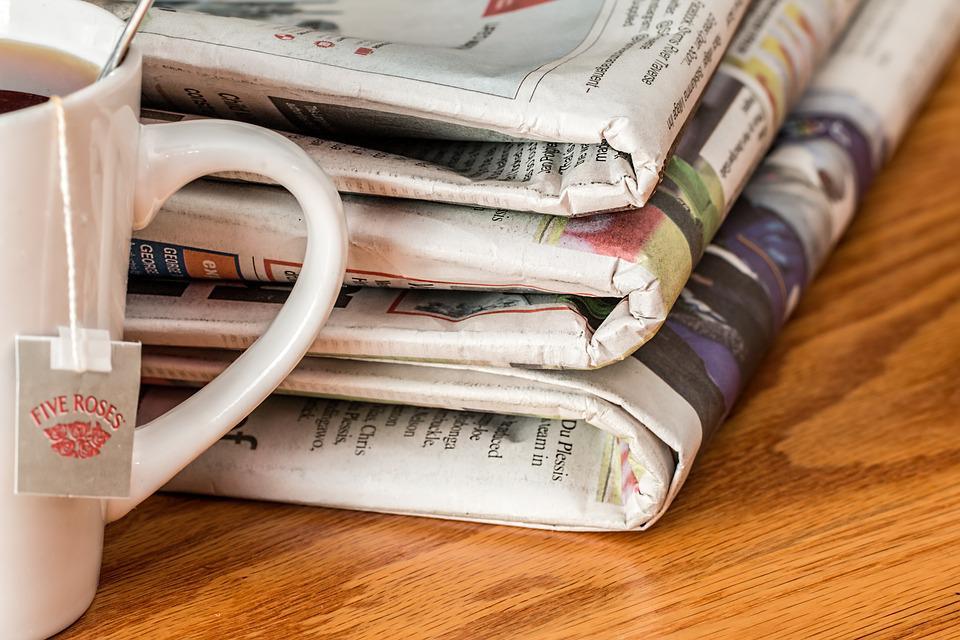 a mug of tea next to a stack of newspapers