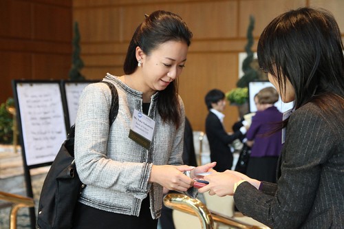 Two business people use both hands to exchange business cards.