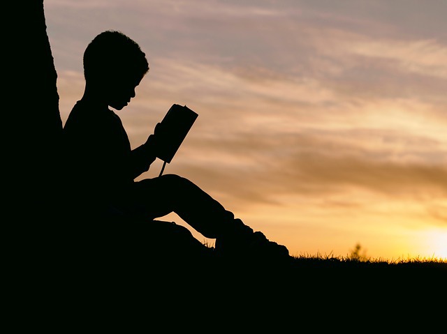 silhouette of a boy reading