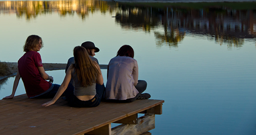 a group of youths on a dock overlooking a body of water.